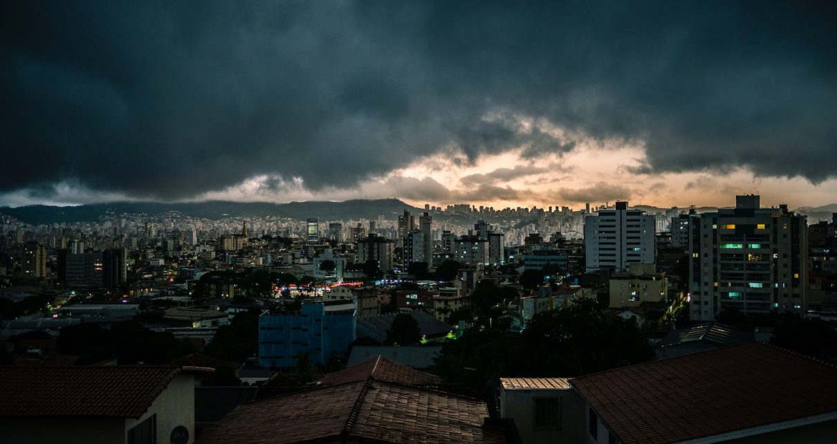 city with high rise buildings under gray clouds during night time